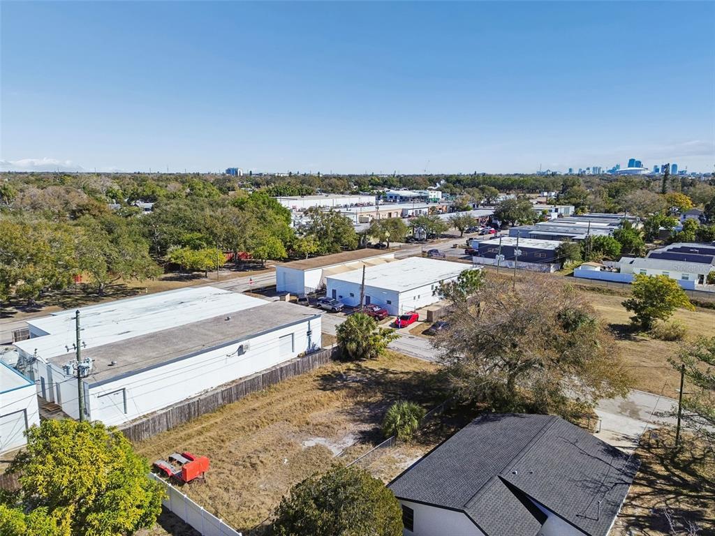 An aerial view shows industrial buildings, a vacant lot, and a residential house under clear skies — 42ND ST S, ST PETERSBURG, FL