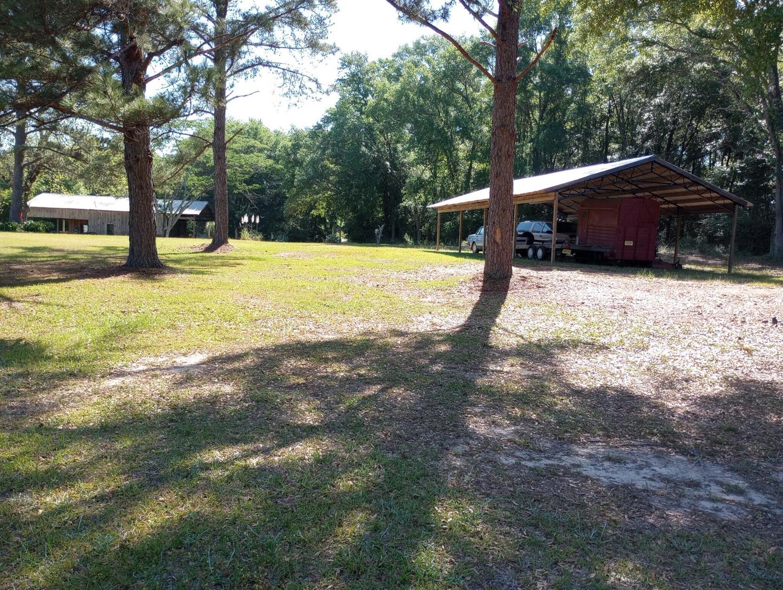 A rustic wooden barn with a metal roof and an attached carport sits on grass — 1900 Olive Lane, FL 32425, FL