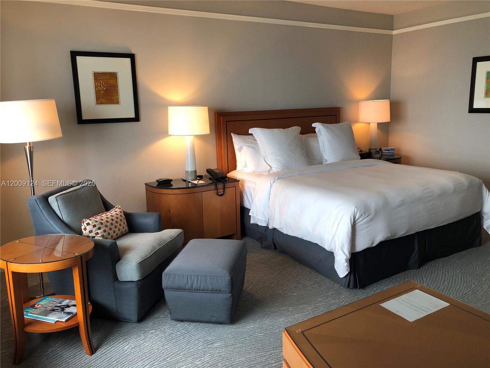 A bedroom features a bed, a gray armchair with an ottoman, and two bedside lamps — 1435 Brickell Ave # 3505, Miami FL 33131, MIAMI, FL