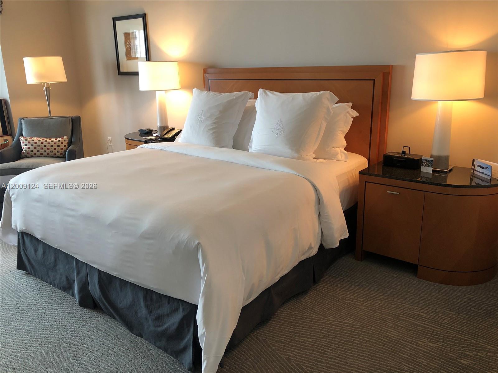 A hotel-style bedroom features a queen bed, two nightstands with lamps, and a gray armchair — 1435 Brickell Ave # 3505, Miami FL 33131, MIAMI, FL