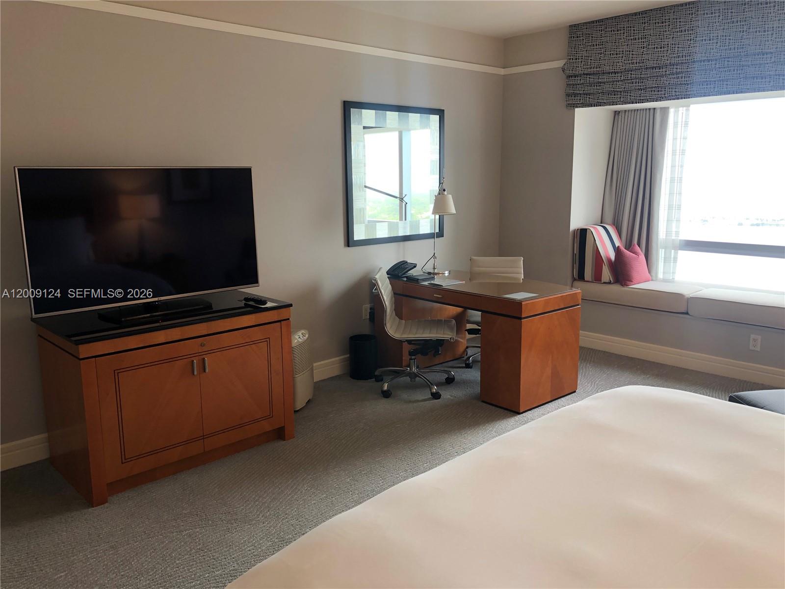 A bedroom features a television on a wooden cabinet, a desk, and a window seat — 1435 Brickell Ave # 3505, Miami FL 33131, MIAMI, FL