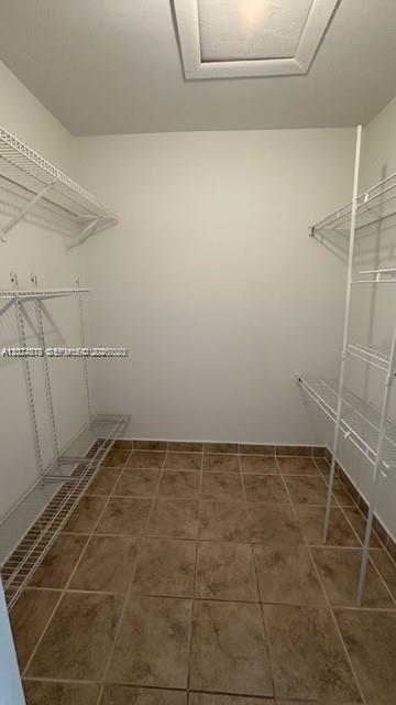 A walk-in closet with white wire shelving and brown tiled flooring — MIAMI, FL