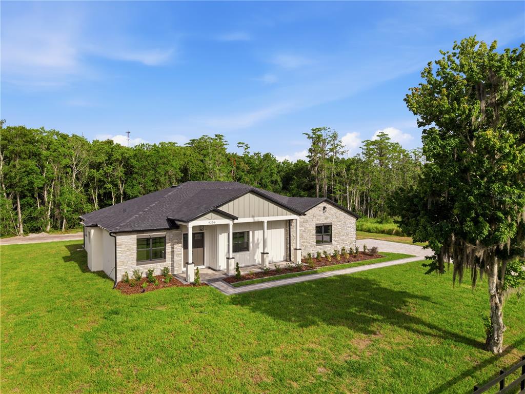 A single-story house with stone and siding exterior sits on a grassy lot near trees — 4256 LA SALLE AVE, ST CLOUD, FL