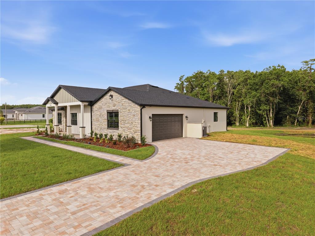 A single-story house with a stone facade, dark garage door, and a paved driveway — 4256 LA SALLE AVE, ST CLOUD, FL