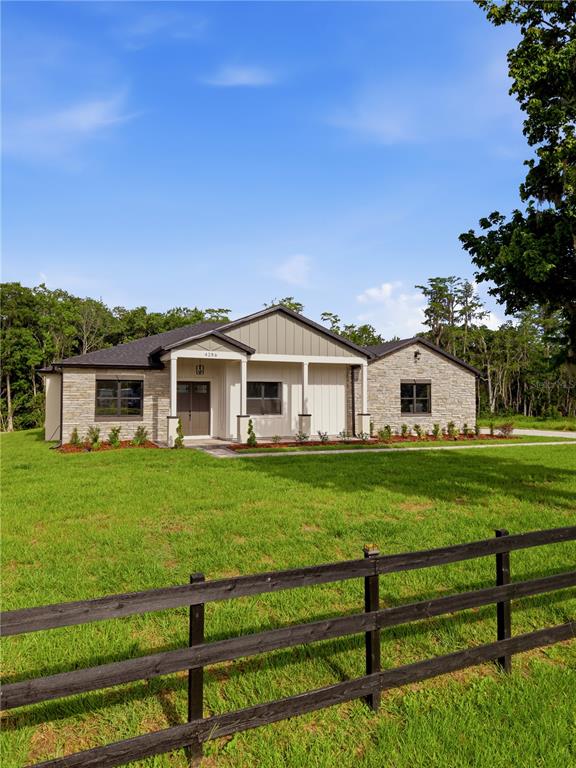 A single-story house with stone siding and a covered porch sits behind a wooden fence — 4256 LA SALLE AVE, ST CLOUD, FL