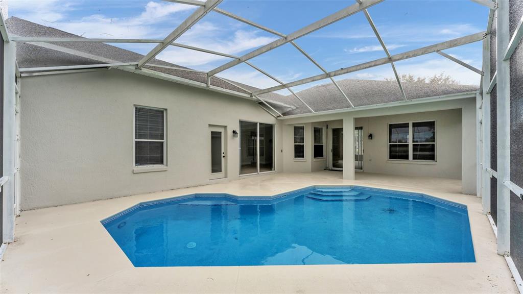 A screened-in patio features a swimming pool with steps and light-colored concrete decking — 1612 FOREST HILLS LANE, HAINES CITY, FL