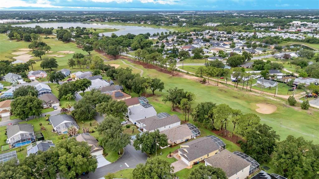 An aerial view shows a residential neighborhood bordering a golf course and a large lake — 1612 FOREST HILLS LANE, HAINES CITY, FL
