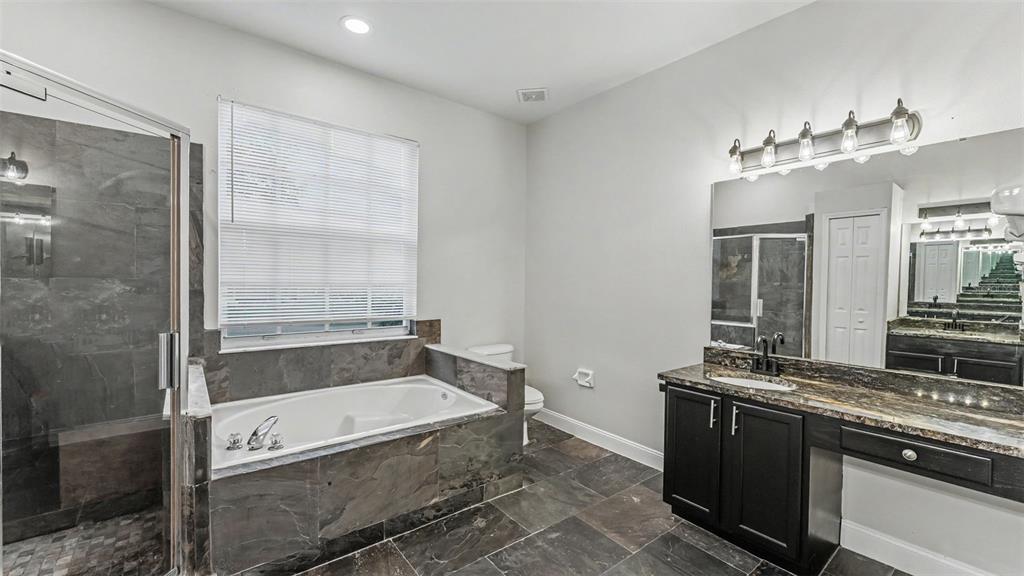 A bathroom features a tiled soaking tub, a glass shower, and a dark wood vanity — 1612 FOREST HILLS LANE, HAINES CITY, FL