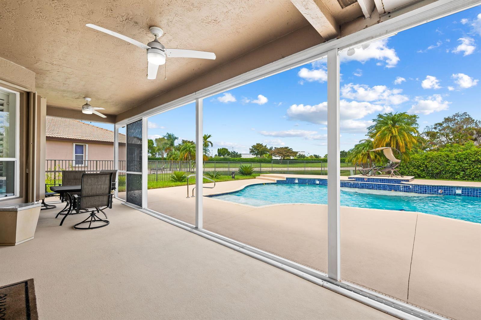 A covered patio with ceiling fans overlooks a swimming pool and a fenced backyard — 12781 Yardley Drive, Boca Raton FL 33428, BOCA RATON, FL