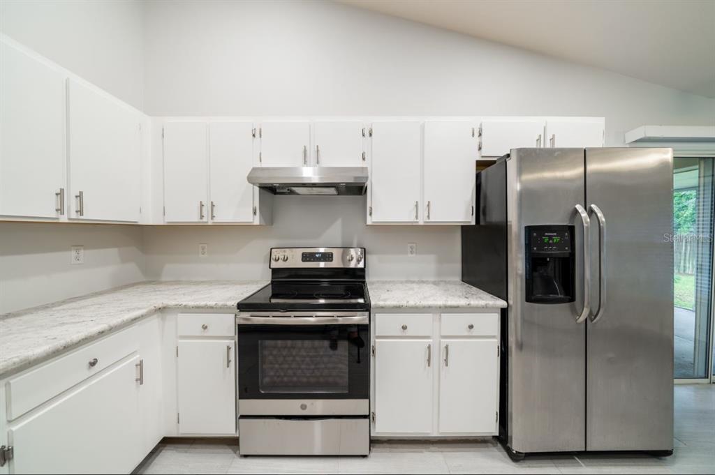A kitchen with white cabinets, stainless steel appliances, and light-colored granite countertops — 7136 SW 81ST DRIVE, GAINESVILLE, FL