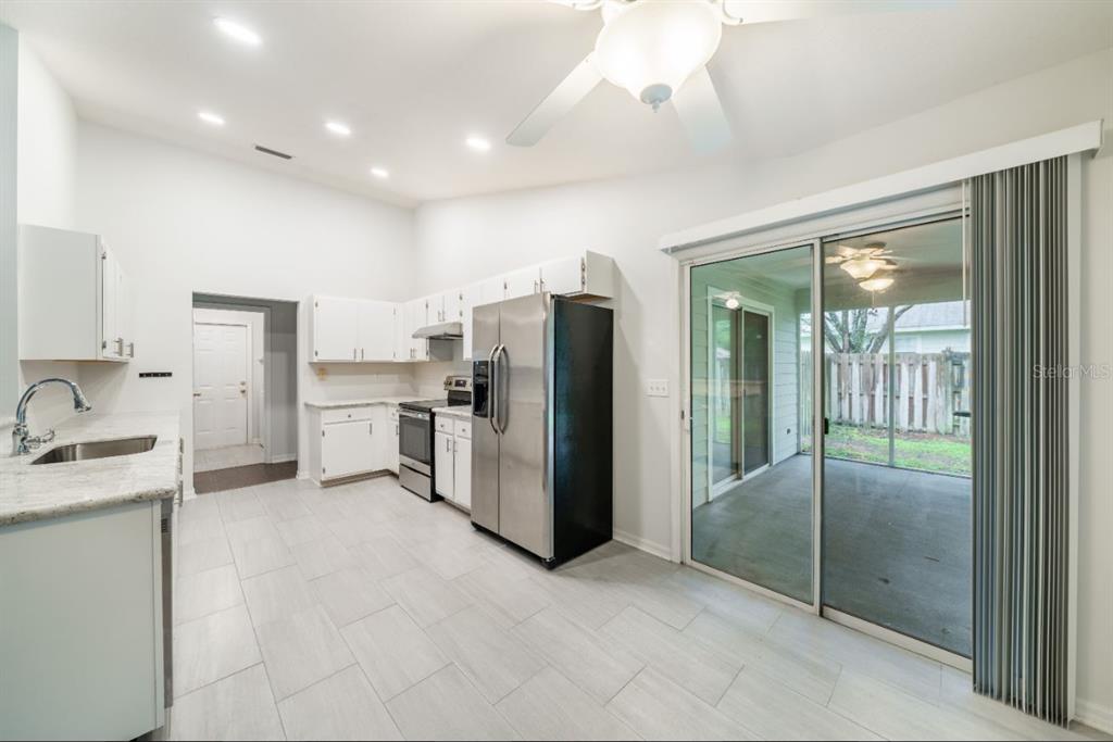 A kitchen with white cabinets, stainless steel appliances, and a sliding glass door to a patio — 7136 SW 81ST DRIVE, GAINESVILLE, FL