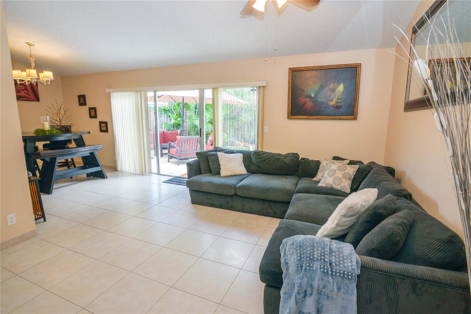A living room with tile floors, a large sectional sofa, and sliding glass doors to a patio — 18813 Cloud Lake Circle, Boca Raton FL 33496, BOCA RATON, FL