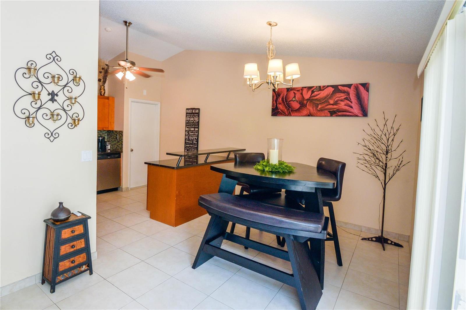 A dining area with a dark wood table, bench, chairs, and a kitchen island — 18813 Cloud Lake Circle, Boca Raton FL 33496, BOCA RATON, FL