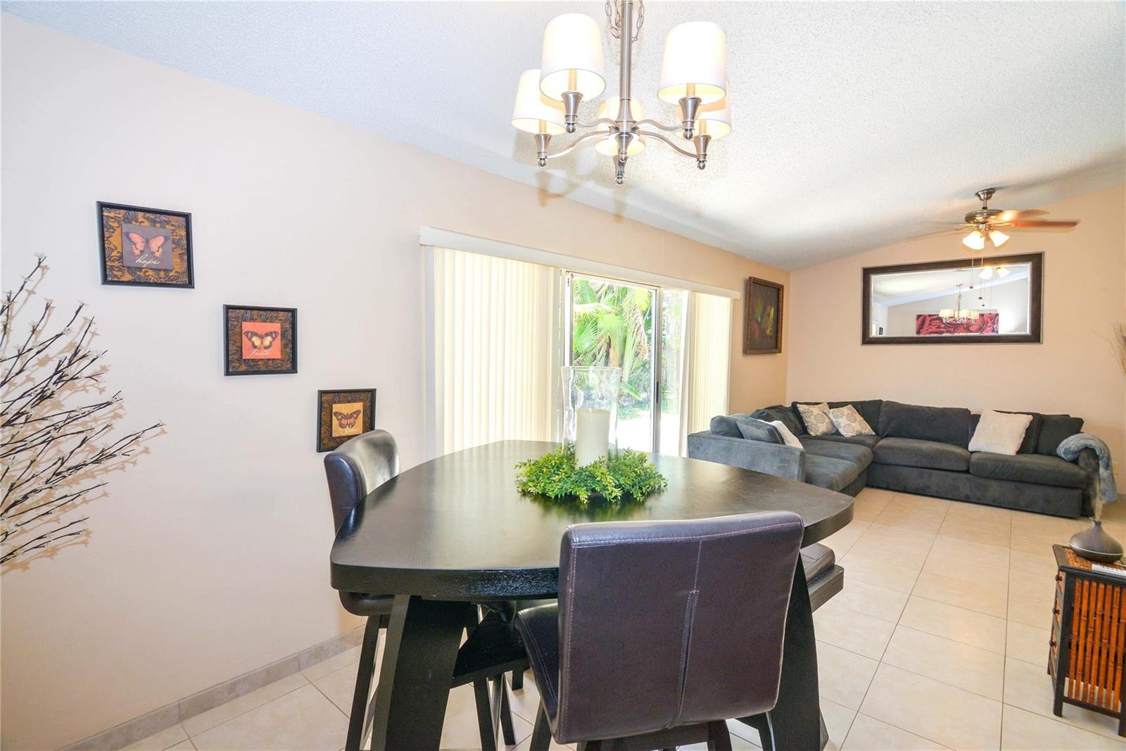 A dining area with a triangular table and chairs sits adjacent to a living room — 18813 Cloud Lake Circle, Boca Raton FL 33496, BOCA RATON, FL
