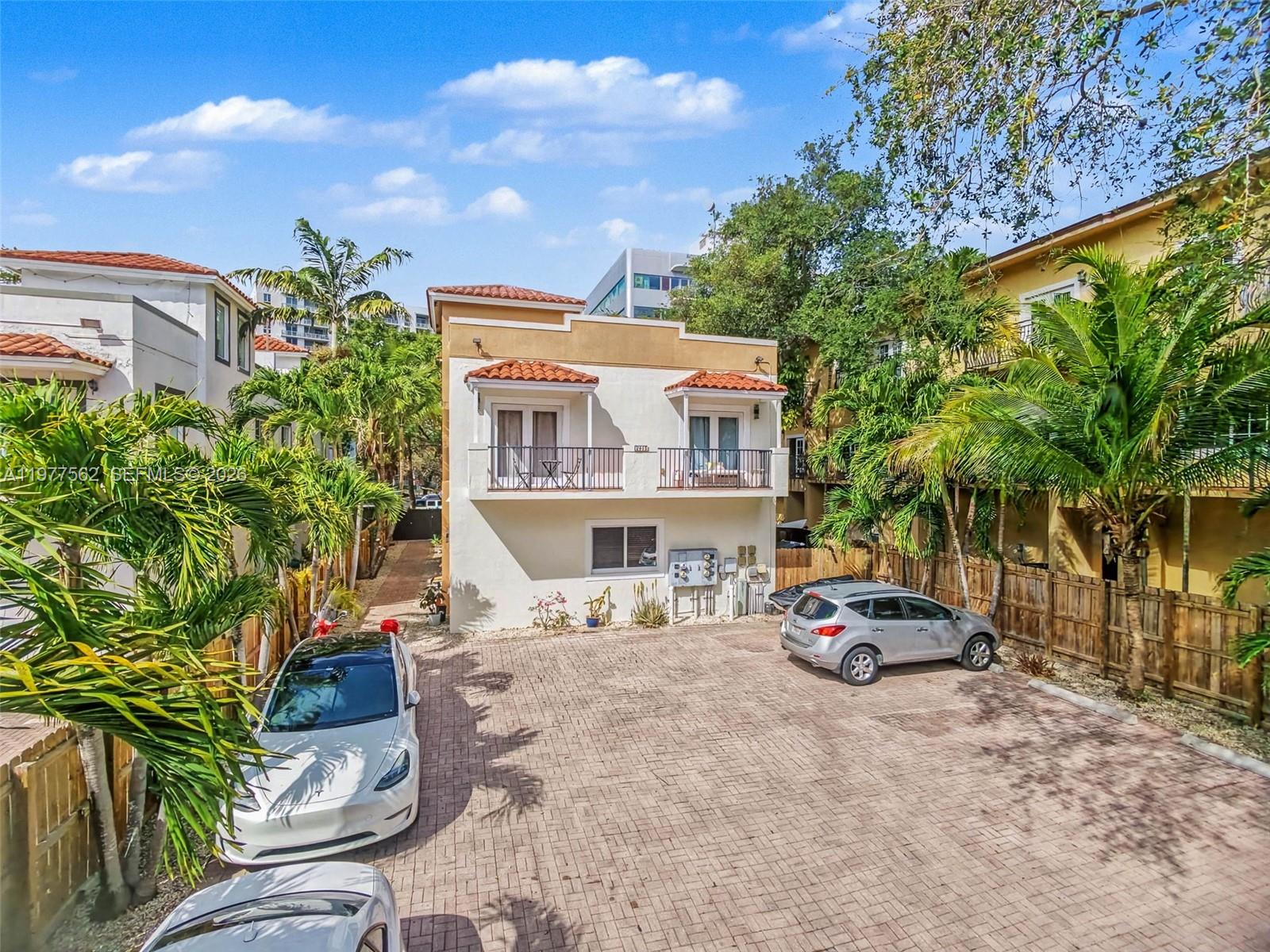 A narrow brick walkway leads between two multi-story buildings lined with palm trees and fencing — 2945 Coconut Ave, Miami FL 33133, MIAMI, FL