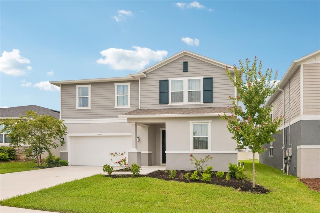 A two-story suburban house with gray siding, a white garage, and a landscaped front yard — 9963 SUNRISE VIEW COURT, SEFFNER, FL