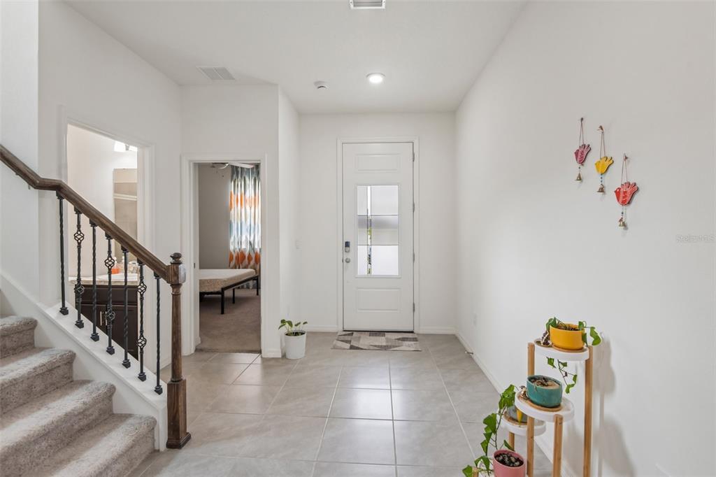 A bright entryway features tiled floors, a staircase with a wooden railing, and a front door — 9963 SUNRISE VIEW COURT, SEFFNER, FL