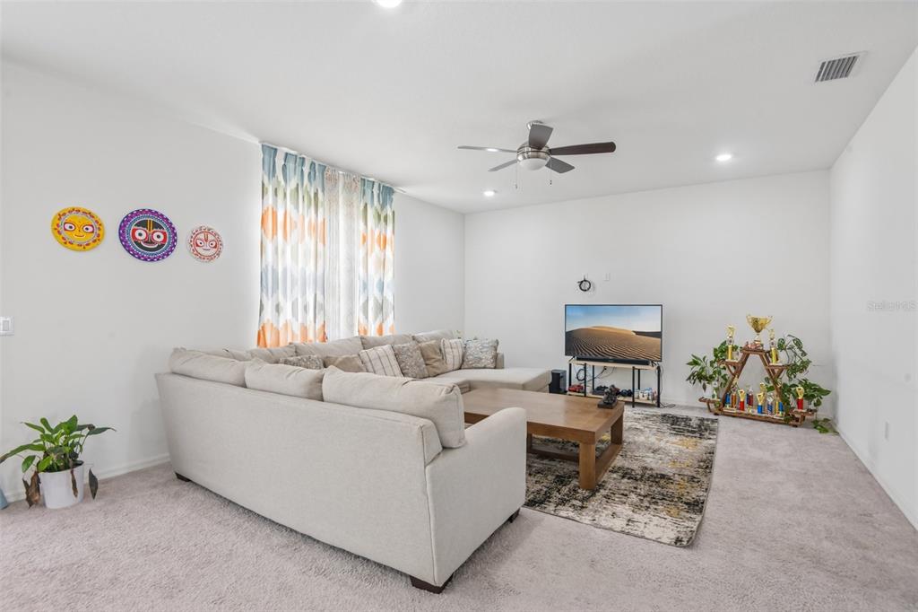 A living room features a large sectional sofa, a coffee table, and a television stand — 9963 SUNRISE VIEW COURT, SEFFNER, FL