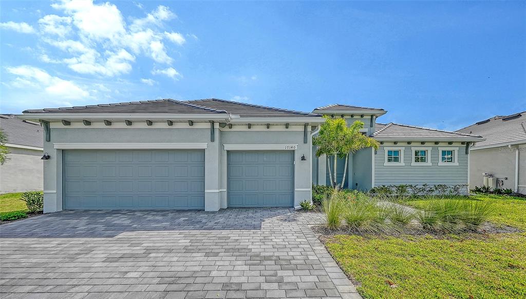 A single-story house with a gray exterior, a three-car garage, and a paved driveway — 17140 ALBATROSS ROAD, VENICE, FL