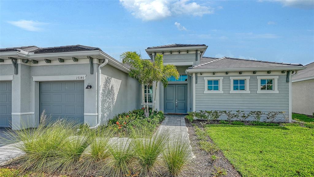A single-story house with a gray exterior, a paved walkway, and a double-door entrance — 17140 ALBATROSS ROAD, VENICE, FL