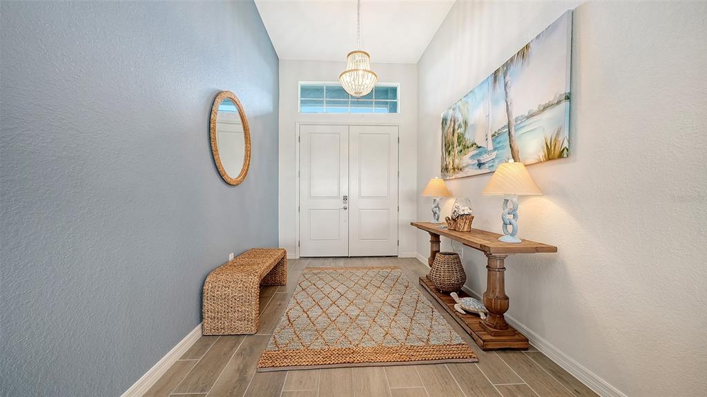 A bright entryway features a blue accent wall, a wooden console table, and a rug — 17140 ALBATROSS ROAD, VENICE, FL
