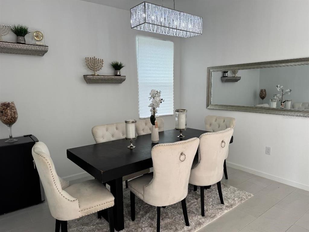 A dining room features a dark table, tufted chairs, a crystal chandelier, and a large mirror — 441 SILVER PALM DRIVE, HAINES CITY, FL