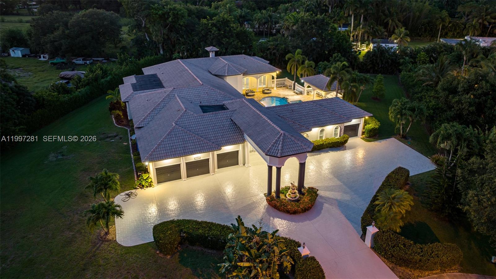 An aerial view of a large house with a multi-car garage, pool, and paved driveway — 13751 Pine Meadow Ct, Davie FL 33325, DAVIE, FL