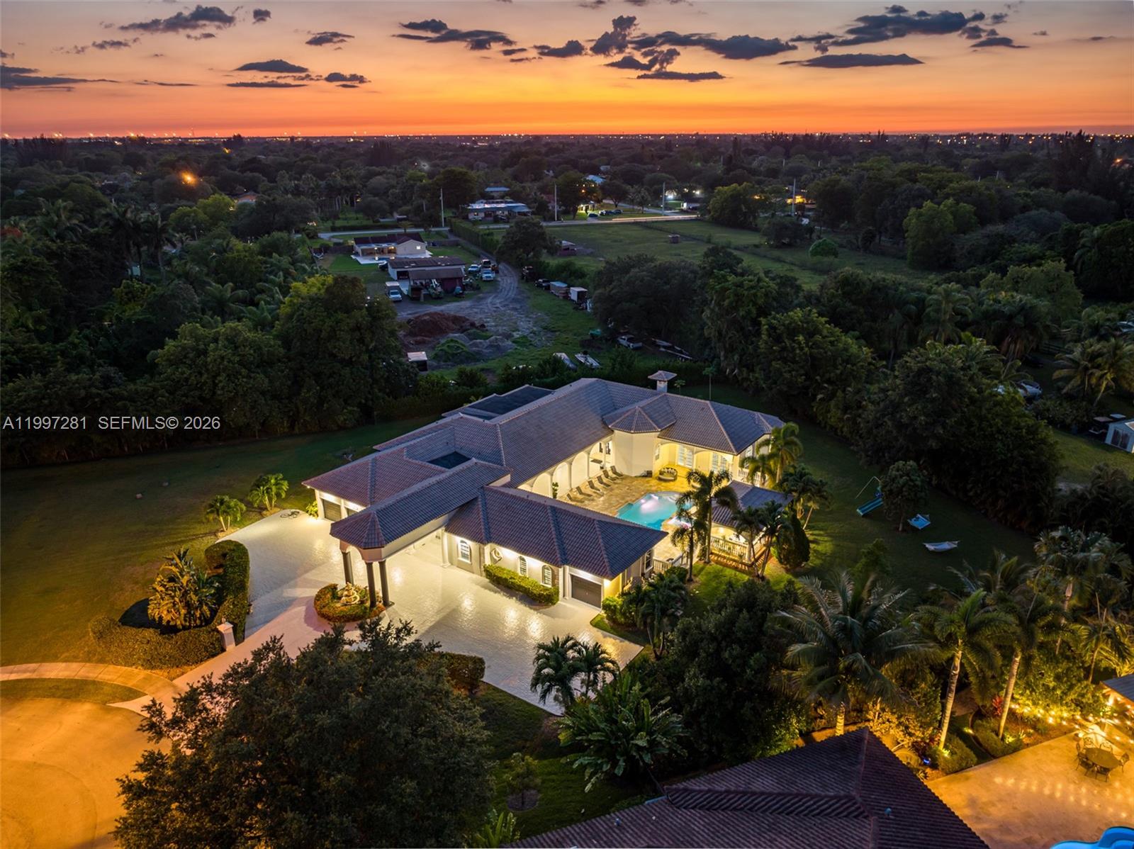 An aerial view shows a large house with a pool and courtyard at sunset — 13751 Pine Meadow Ct, Davie FL 33325, DAVIE, FL
