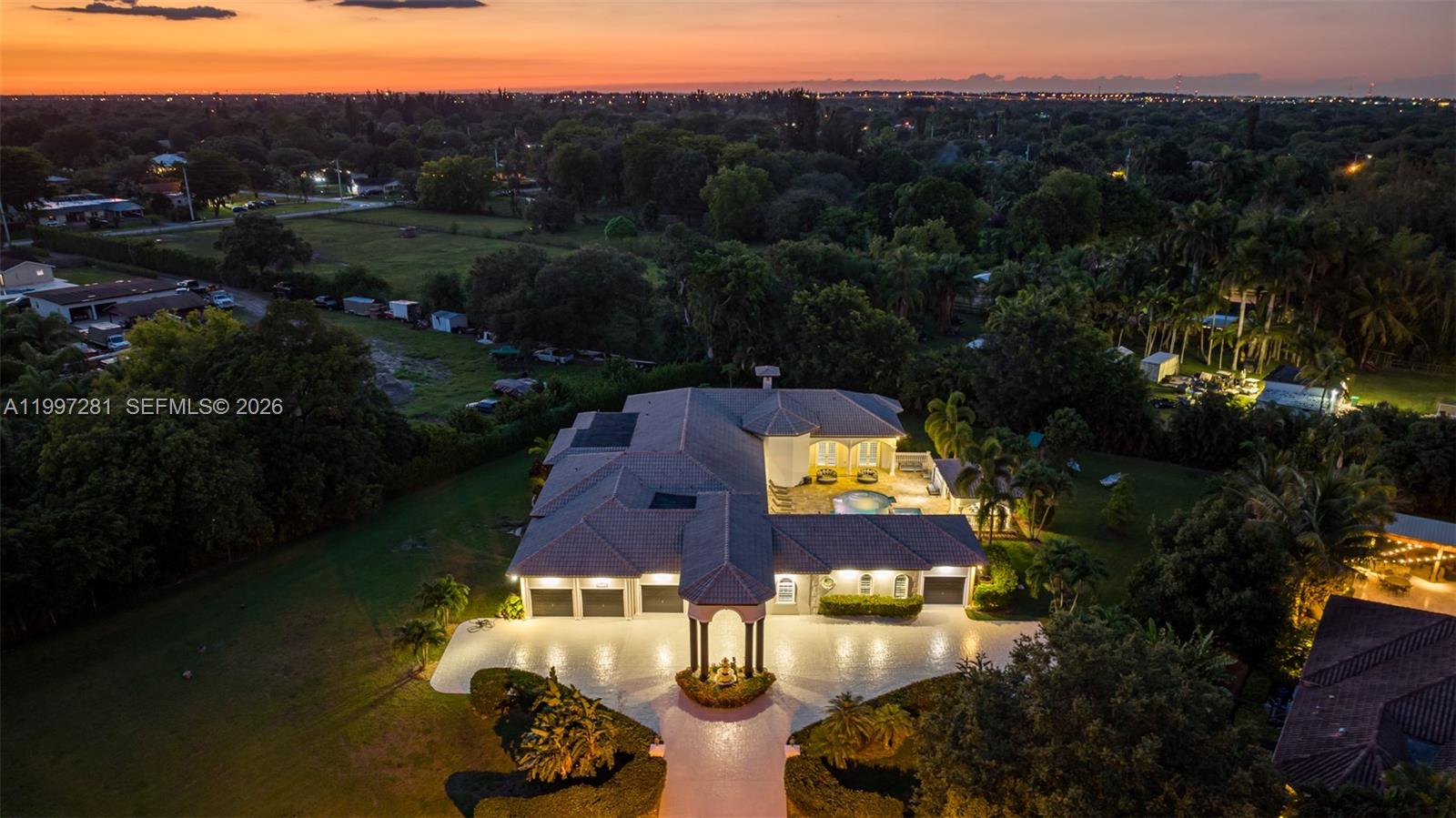 An aerial view of a large house with a pool and circular driveway at sunset — 13751 Pine Meadow Ct, Davie FL 33325, DAVIE, FL