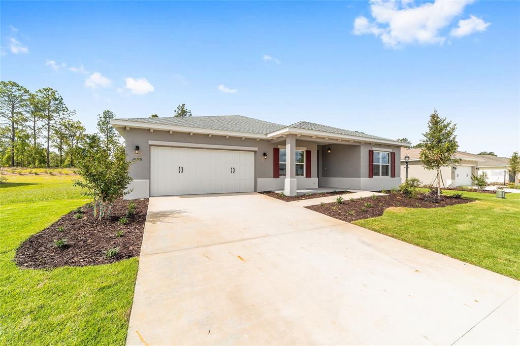 A single-story house with a two-car garage, a concrete driveway, and a covered front porch — 10710 SW 104TH PLACE, OCALA, FL