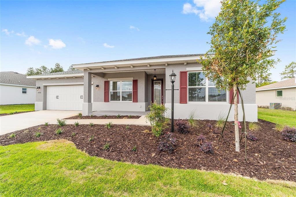 A single-story house with gray stucco siding, red shutters, and a two-car garage — 10710 SW 104TH PLACE, OCALA, FL