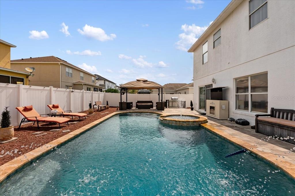 A backyard features a rectangular swimming pool with a spa, lounge chairs, and a gazebo — 2074 RIO GRANDE CANYON LOOP, KISSIMMEE, FL
