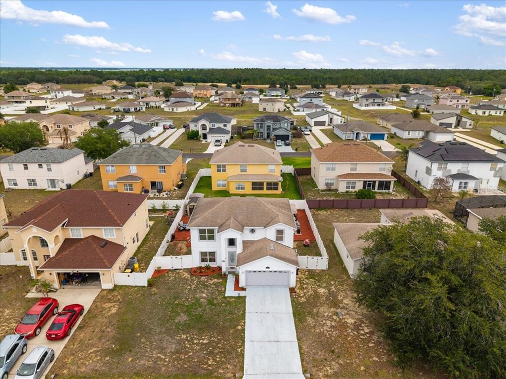 An aerial view shows a suburban neighborhood with detached houses and paved driveways — 2074 RIO GRANDE CANYON LOOP, KISSIMMEE, FL