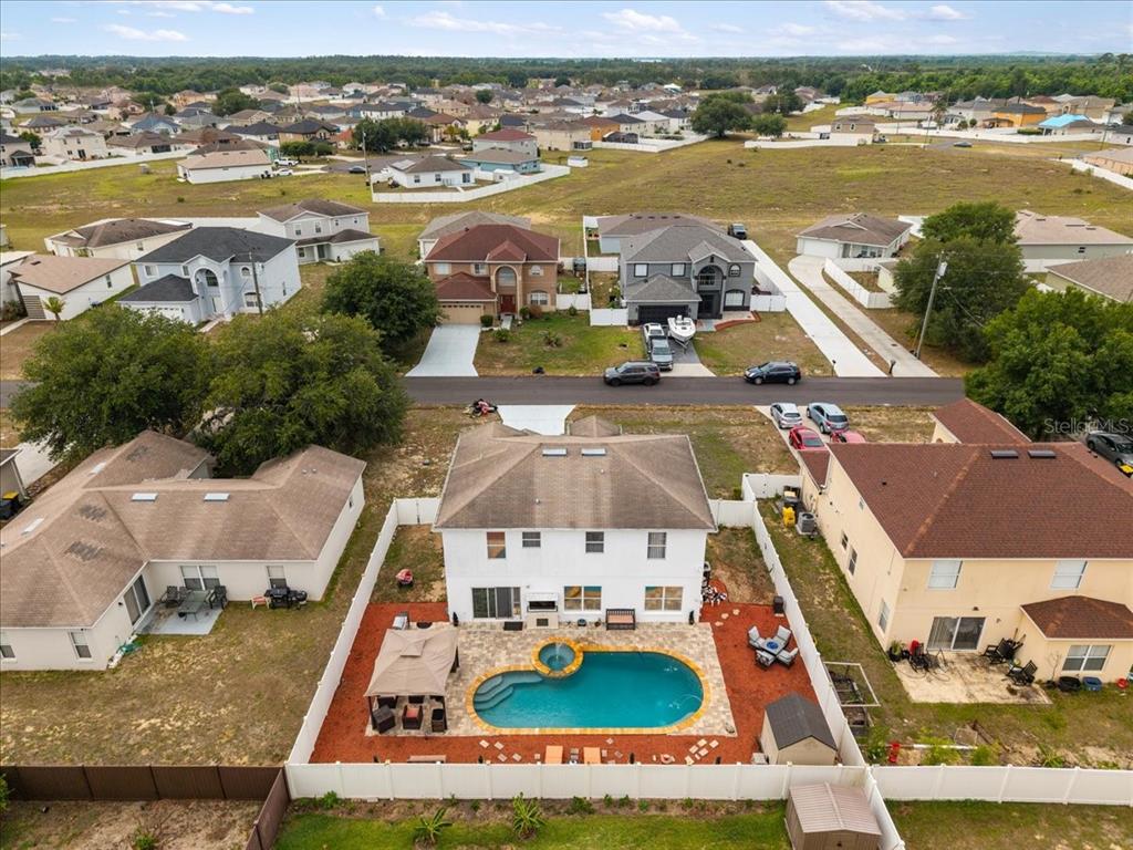 An aerial view shows a two-story house with a backyard pool and white privacy fence — 2074 RIO GRANDE CANYON LOOP, KISSIMMEE, FL