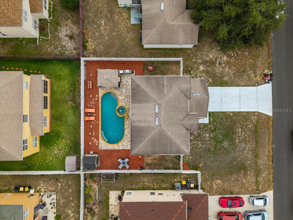An aerial view shows a house with a swimming pool and patio inside a fenced yard — 2074 RIO GRANDE CANYON LOOP, KISSIMMEE, FL