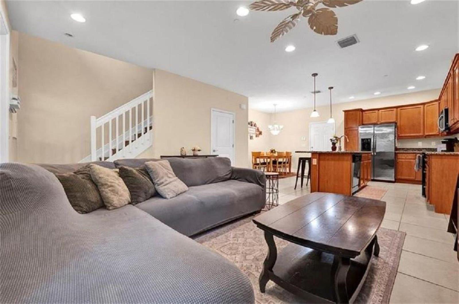 A living room with a grey sectional sofa, coffee table, and an open-concept kitchen — 2930 Cascada Isles Way, Cooper City FL 33024, COOPER CITY, FL