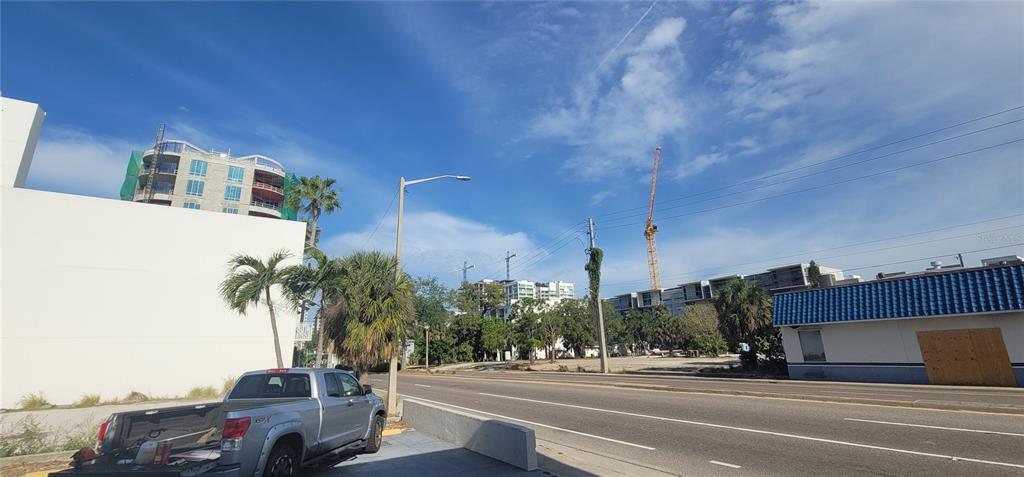 A street-level view shows a pickup truck parked near a vacant lot with construction cranes — 227 CENTRAL AVENUE, SARASOTA, FL