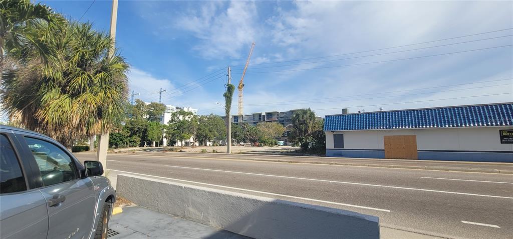A street-level view shows a vacant lot with a construction crane behind a paved road — 227 CENTRAL AVENUE, SARASOTA, FL