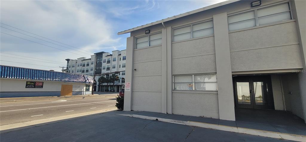 A low-angle exterior view shows a beige commercial building next to a street with traffic — 227 CENTRAL AVENUE, SARASOTA, FL