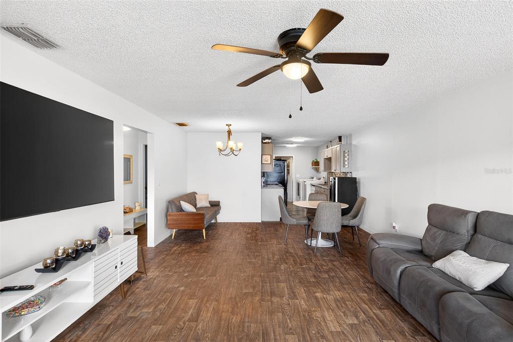 An open-concept living and dining area features wood-look flooring, a ceiling fan, and white walls — 622 RIDGE TERRACE, WINTER HAVEN, FL