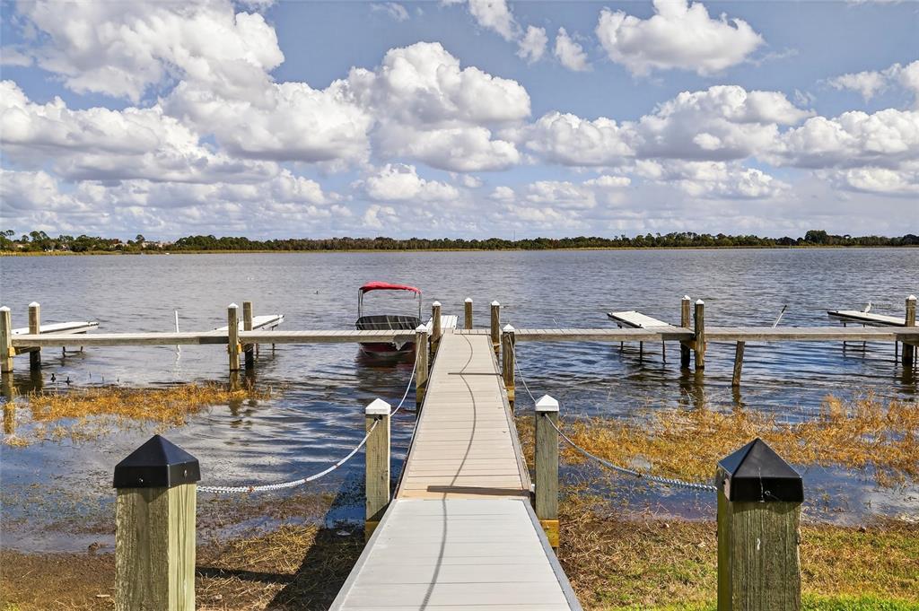 A wooden dock with a boat slip extends into a lake under a cloudy sky — 622 RIDGE TERRACE, WINTER HAVEN, FL