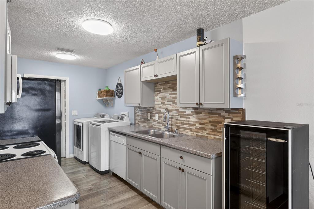 A laundry room featuring grey cabinets, a stainless steel sink, and a wine cooler — 622 RIDGE TERRACE, WINTER HAVEN, FL