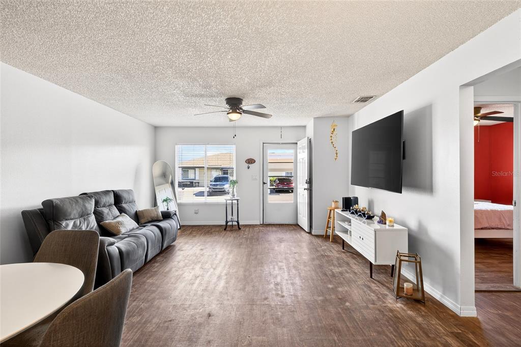 A living room features wood-look flooring, a gray sofa, a wall-mounted television, and a ceiling fan — 622 RIDGE TERRACE, WINTER HAVEN, FL