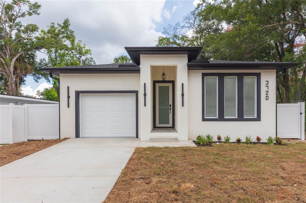 A modern, single-story house with white stucco walls, a dark trim, and a concrete driveway — 3720 N 32ND, TAMPA, FL