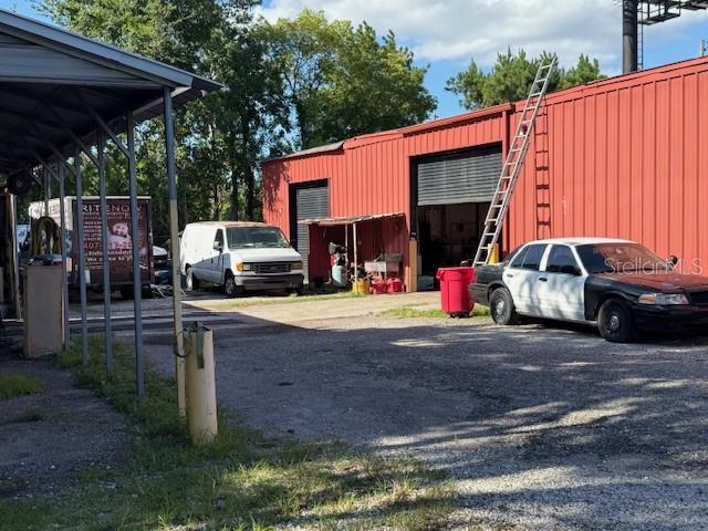 A red metal industrial building with a ladder, a white van, and a police cruiser — 644 MAGUIRE ROAD, OCOEE, FL