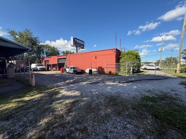 A red industrial building with a large billboard stands on a gravel lot — 644 MAGUIRE ROAD, OCOEE, FL