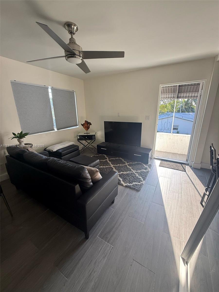 A living room features a black sofa, a television on a stand, and a balcony door — 241 NW 34th Ter, Miami FL 33127, MIAMI, FL