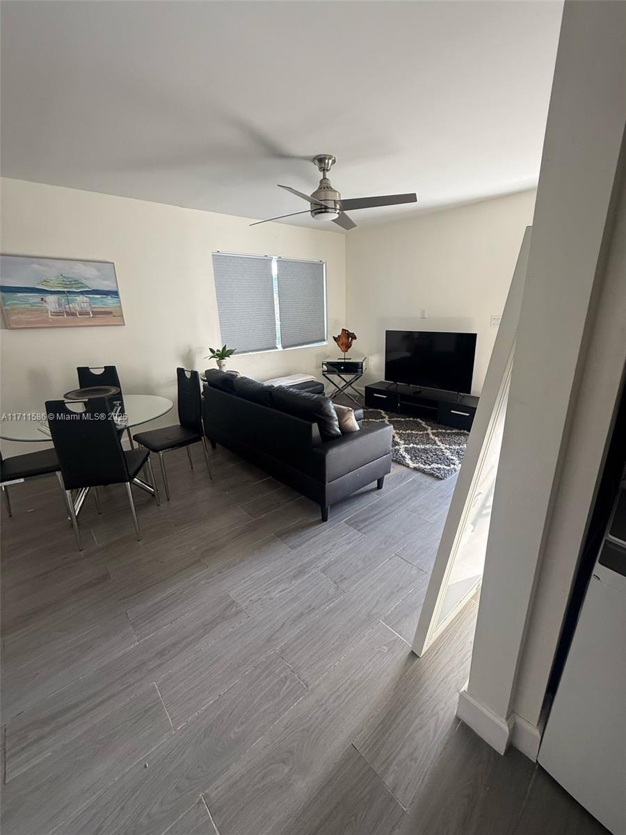 A living room and dining area feature gray tile flooring, a black sofa, and a television — 241 NW 34th Ter, Miami FL 33127, MIAMI, FL