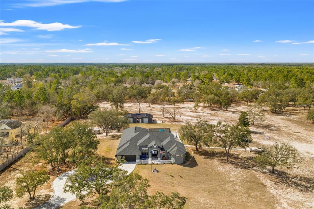An aerial view shows a single-story house with a dark roof and a detached garage — 12277 ESKIMO CURLEW ROAD, WEEKI WACHEE, FL