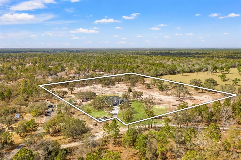 An aerial view shows a house situated on a large, partially wooded lot — 12277 ESKIMO CURLEW ROAD, WEEKI WACHEE, FL